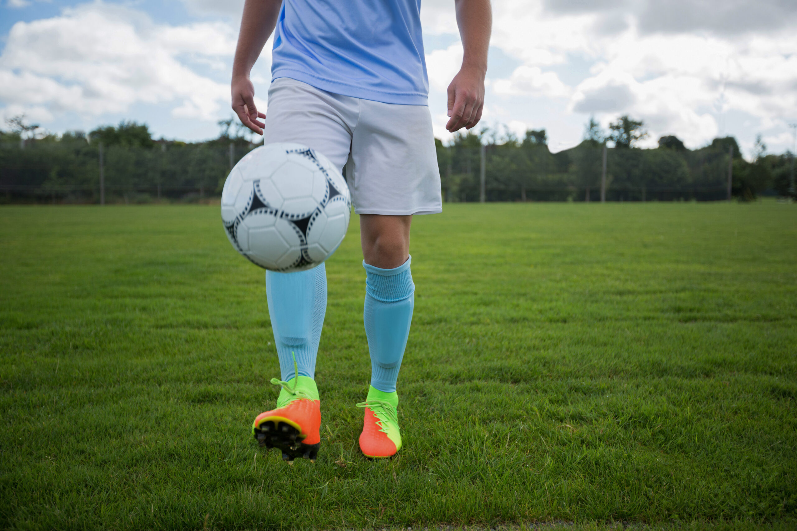Football player juggling soccer ball in the ground